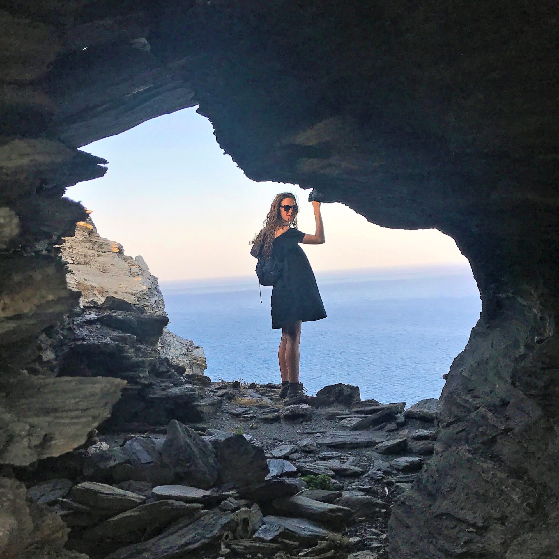 Female student in cave that looks out to the sea.