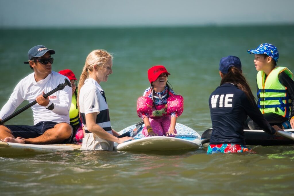 Woman teaching young children to surf