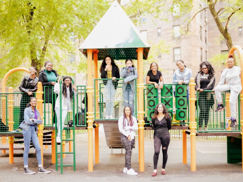 Group of girls standing on climbing frame in playground. 