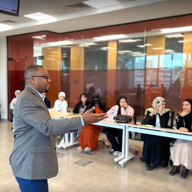 Man presenting to room of students sitting at table