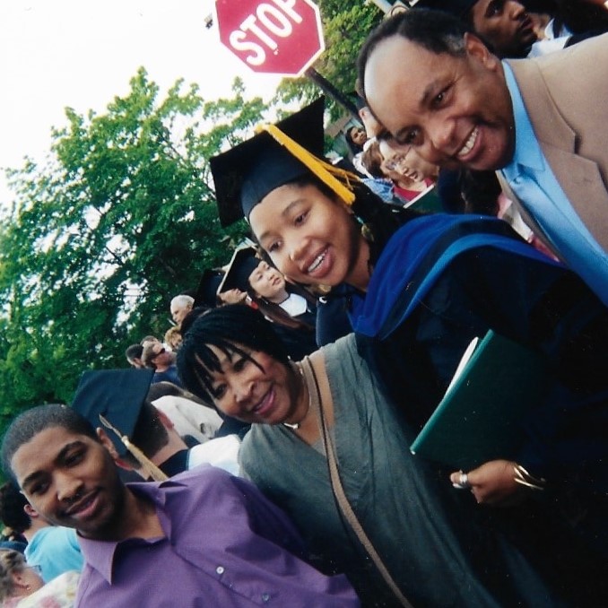 Keshia Abraham standing in cap and gown with family