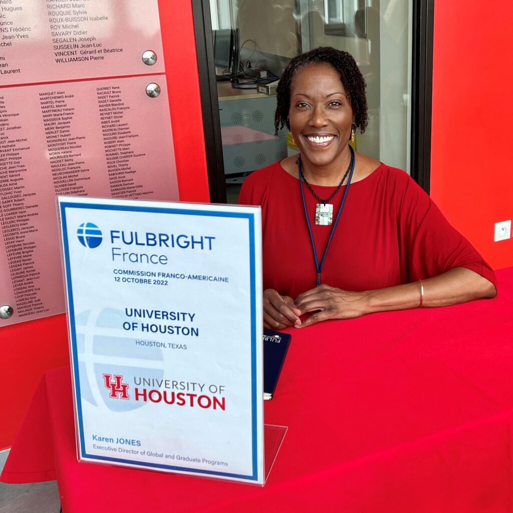 Fulbright scholar sitting at desk with Fulbright sign in front of her