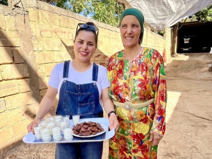 Two women standing together outside and one hold tray with food and drink on