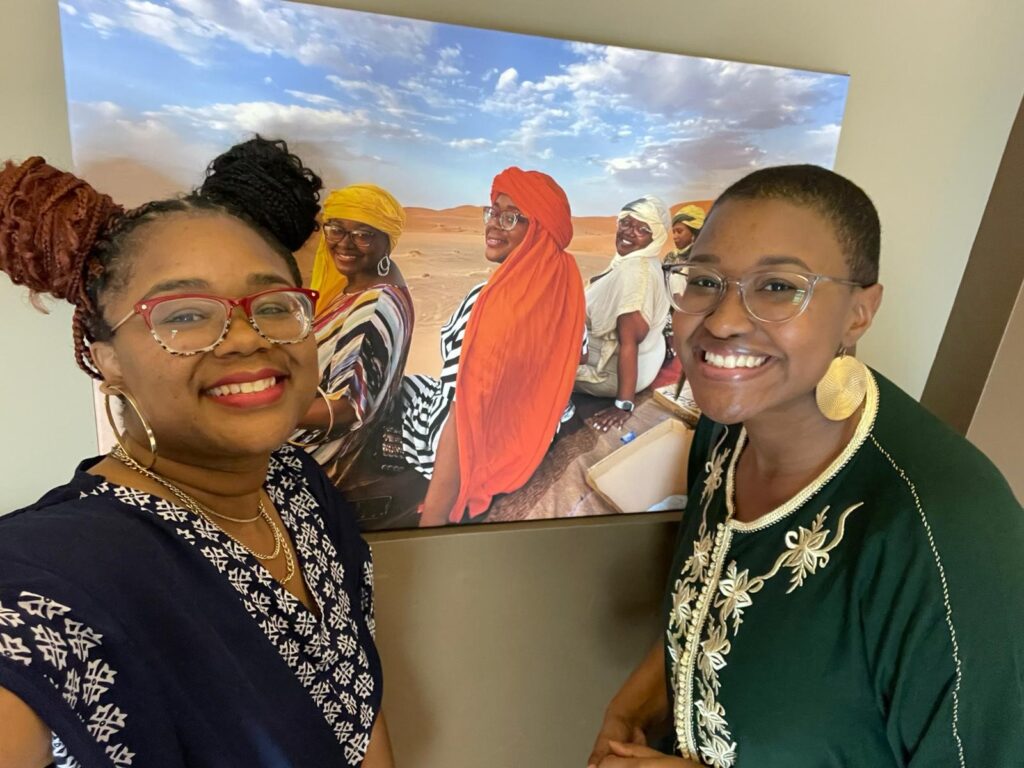 Two women standing in front of picture on wall
