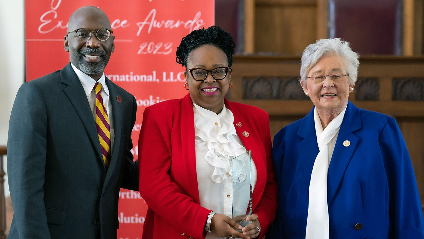 Rhonda Collier standing with two other people holding Trade Excellence Award.