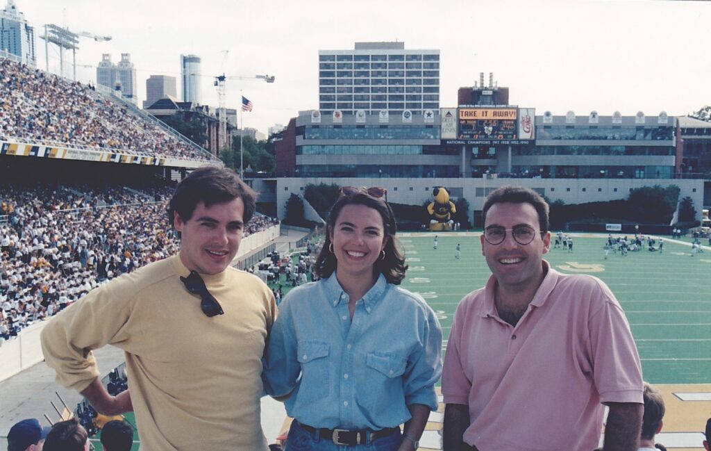 Ángel Cabrera standing with a man and woman with sports field behind them