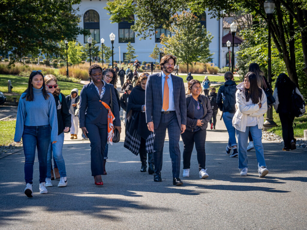 Jonathan Koppell walking with a group of students on a campus pathway