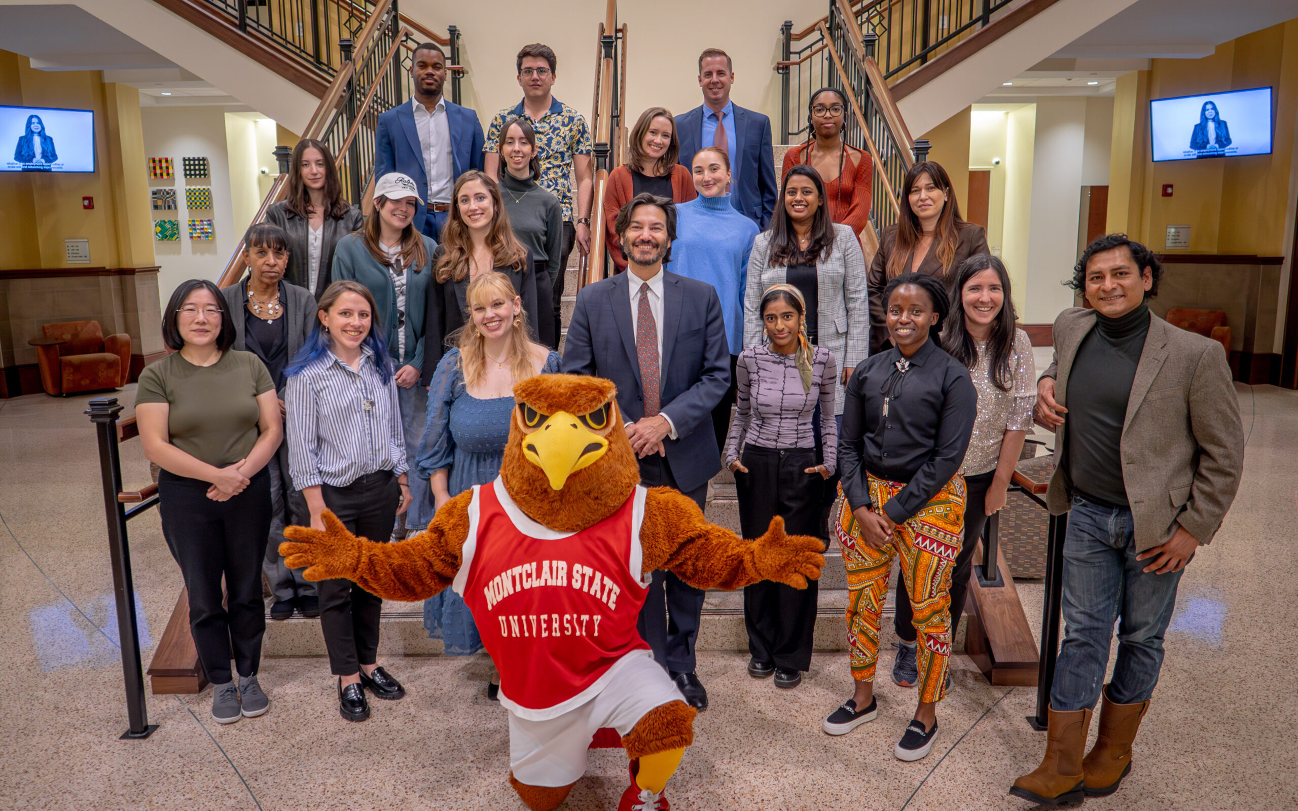 Jonathan Koppell standing on stair with Fulbright students and university mascot