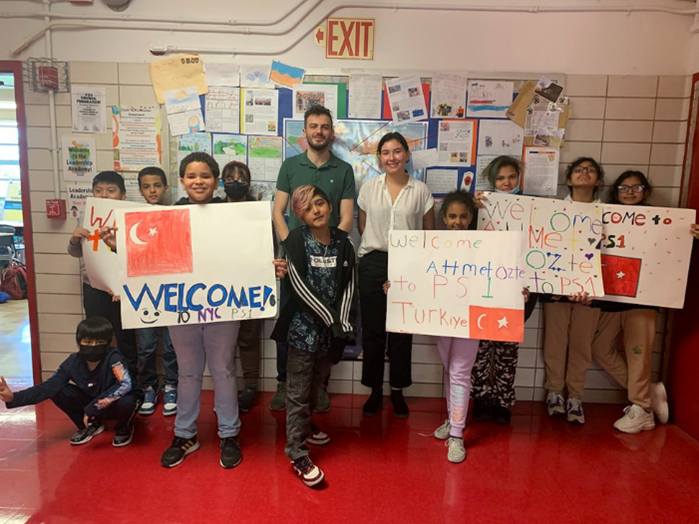 Fulbrighter standing with students holding up artwork