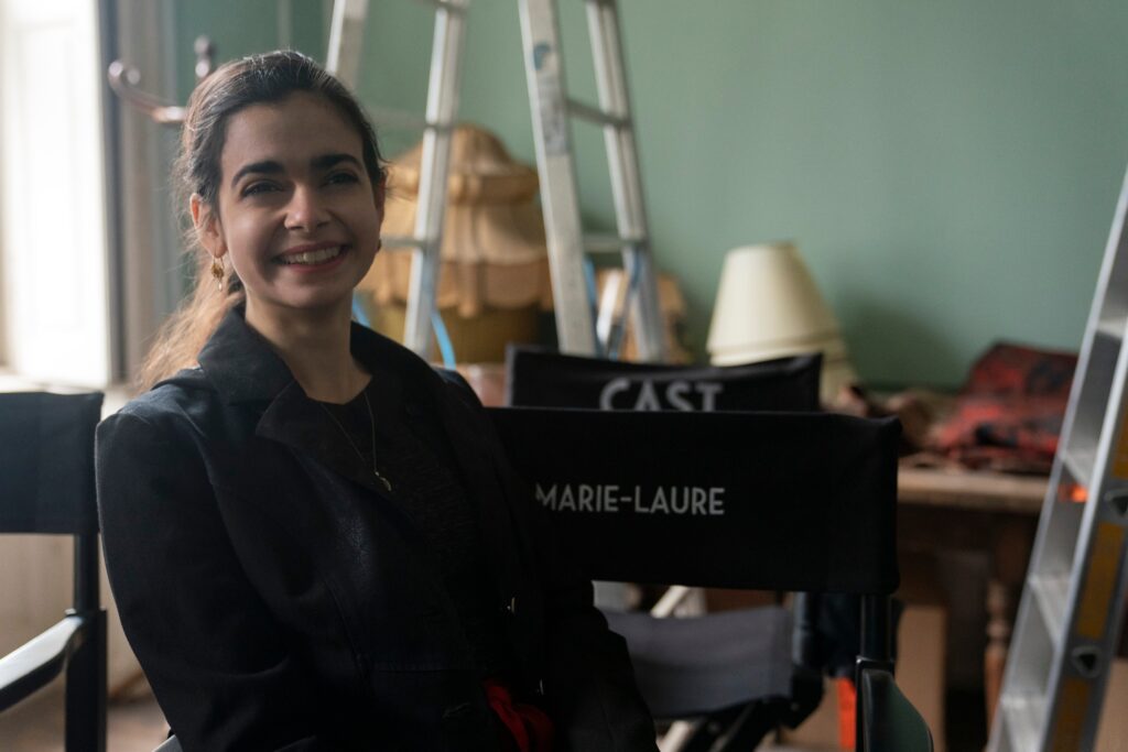 Ari Mia Loberti on set of tv show All the Light We Cannot See sitting in directors chair