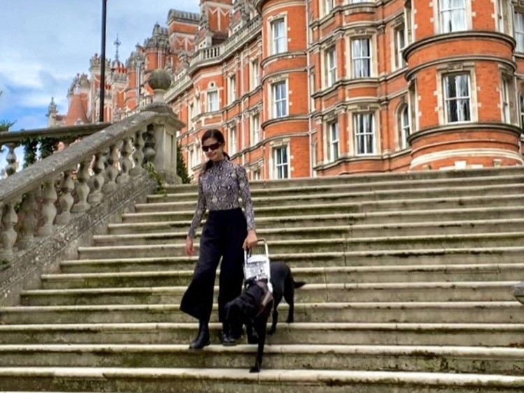 Aria Mia Loberti walking downstairs in London with guide dog