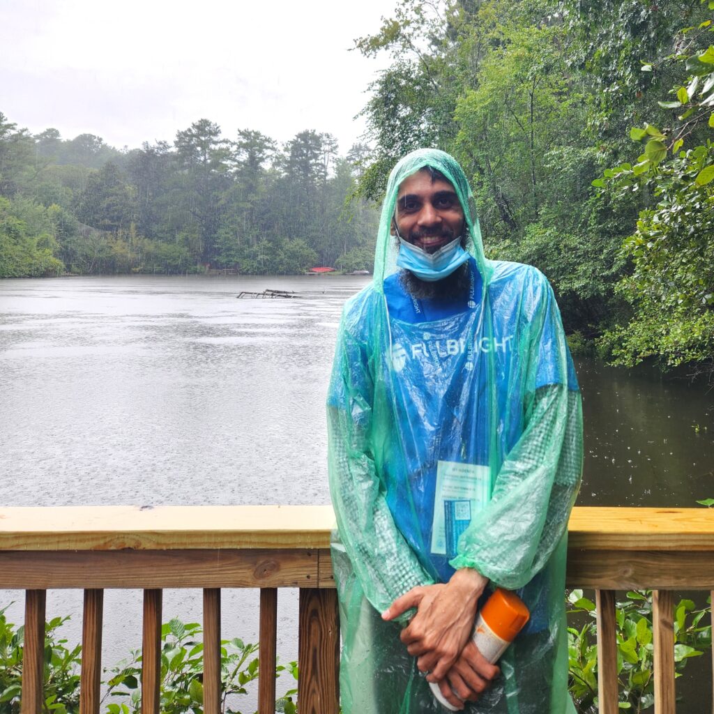 Muhammed standing by lake in rain poncho