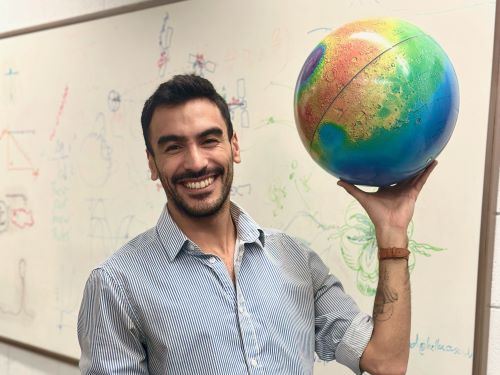 Fulbrighter, Juan Manuel Losarcos, standing in front of whiteboard holding globe