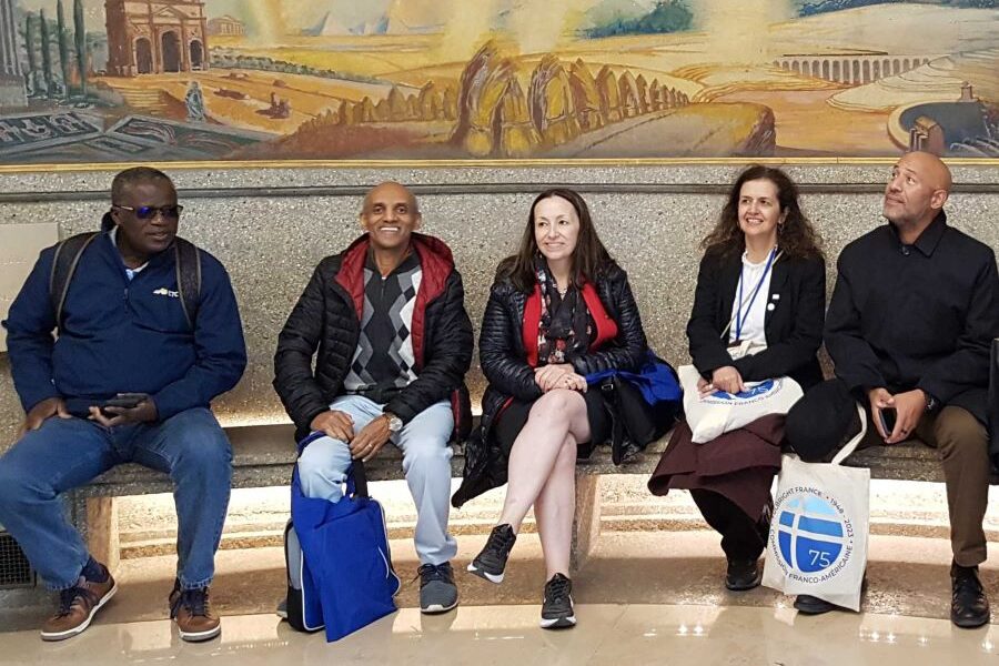 Dr. Koffi Akakpo (left) Dr. Yacob Astatke (second left) sat in front of painting at art gallery.