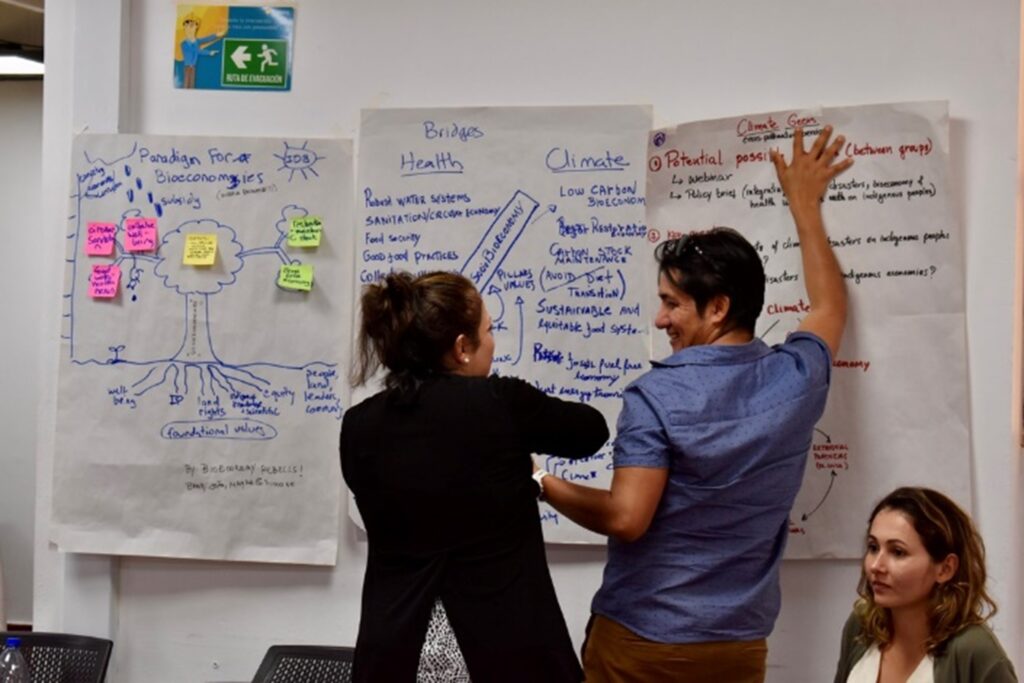 Two Amazonia scholars writing on poster stuck on wall 