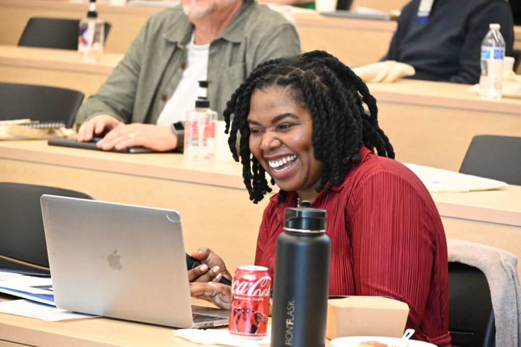 Scholar Liaison laughing and working on laptop