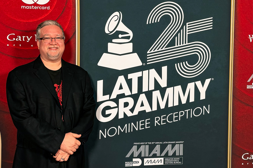 Jamie Ousley stands next to a sign for the 25th Latin Grammy Nominee Reception.