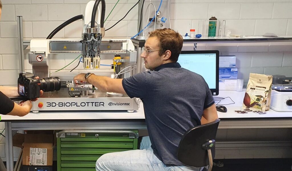 Man operating a 3D-Bioplotter in a lab setting.