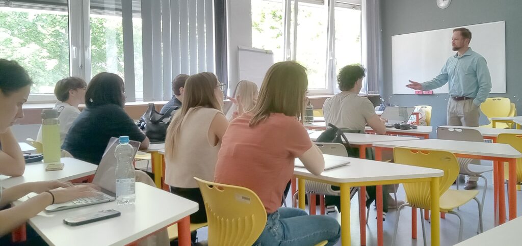 Classroom with students seated at desks and an instructor standing at the front.