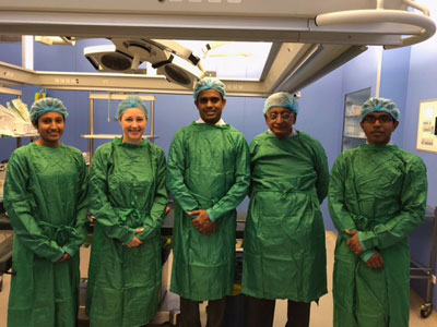 Five doctors in green medical scrub outfits standing in hospital