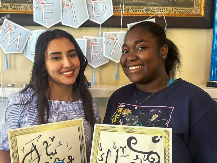 Fulbright Foreign Language Teaching Assistant standing with student both holding calligraphy artwork