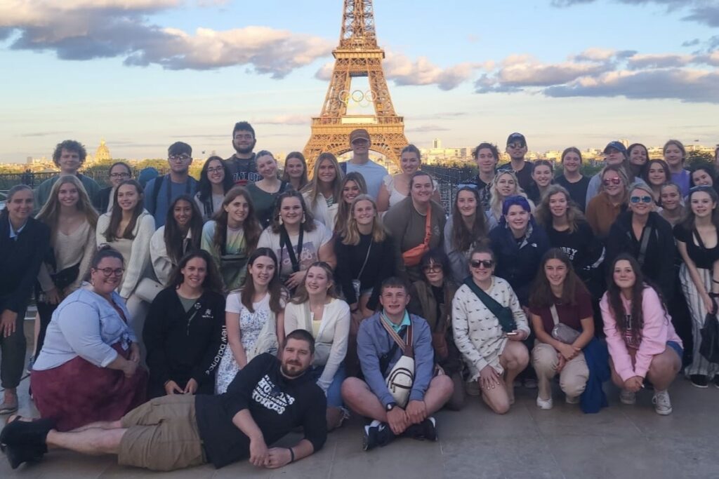 Ashlie Crosson in a large group of people posing together in front of the Eiffel Tower in Paris