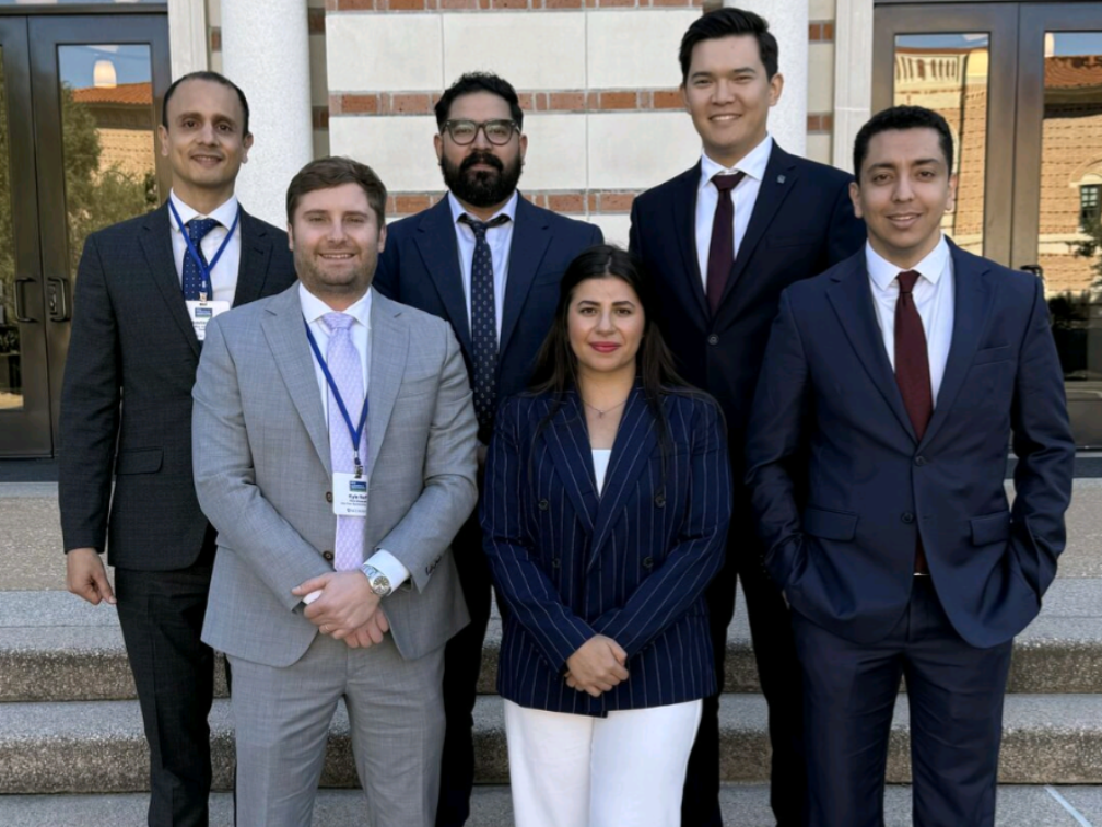 A group of six people in business attire standing on building steps.